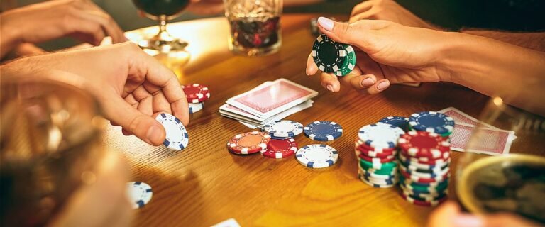 Poker Cash Game: Freunde um einen Tisch, die Poker spielen Pokerchips und Karten liegen auf dem Tisch.