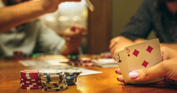 Poker lernen: Spieler an einem Spieltisch mit Karten in der Hand und Pokerchip auf dem Tisch