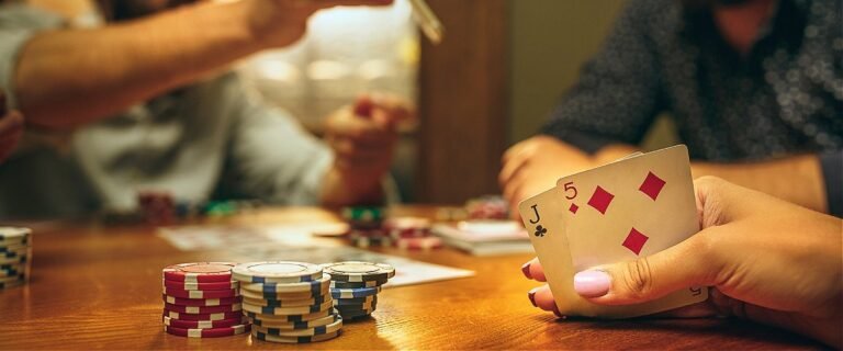 Poker lernen: Spieler an einem Spieltisch mit Karten in der Hand und Pokerchip auf dem Tisch